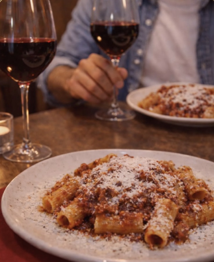 Rigatoni e calici di vino rosso a lume di candela da Romano Vino e Cucina